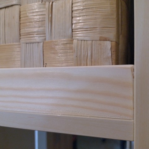Detail-Ansicht eines Regals mit einer eingeleimten Holzleiste und einer Kiste dahinter