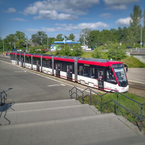 Eine Straßenbahn am Gelände des egaparks in Erfurt, im Vordergrund eine breite Treppe, im Hintergrund eine Tankstelle