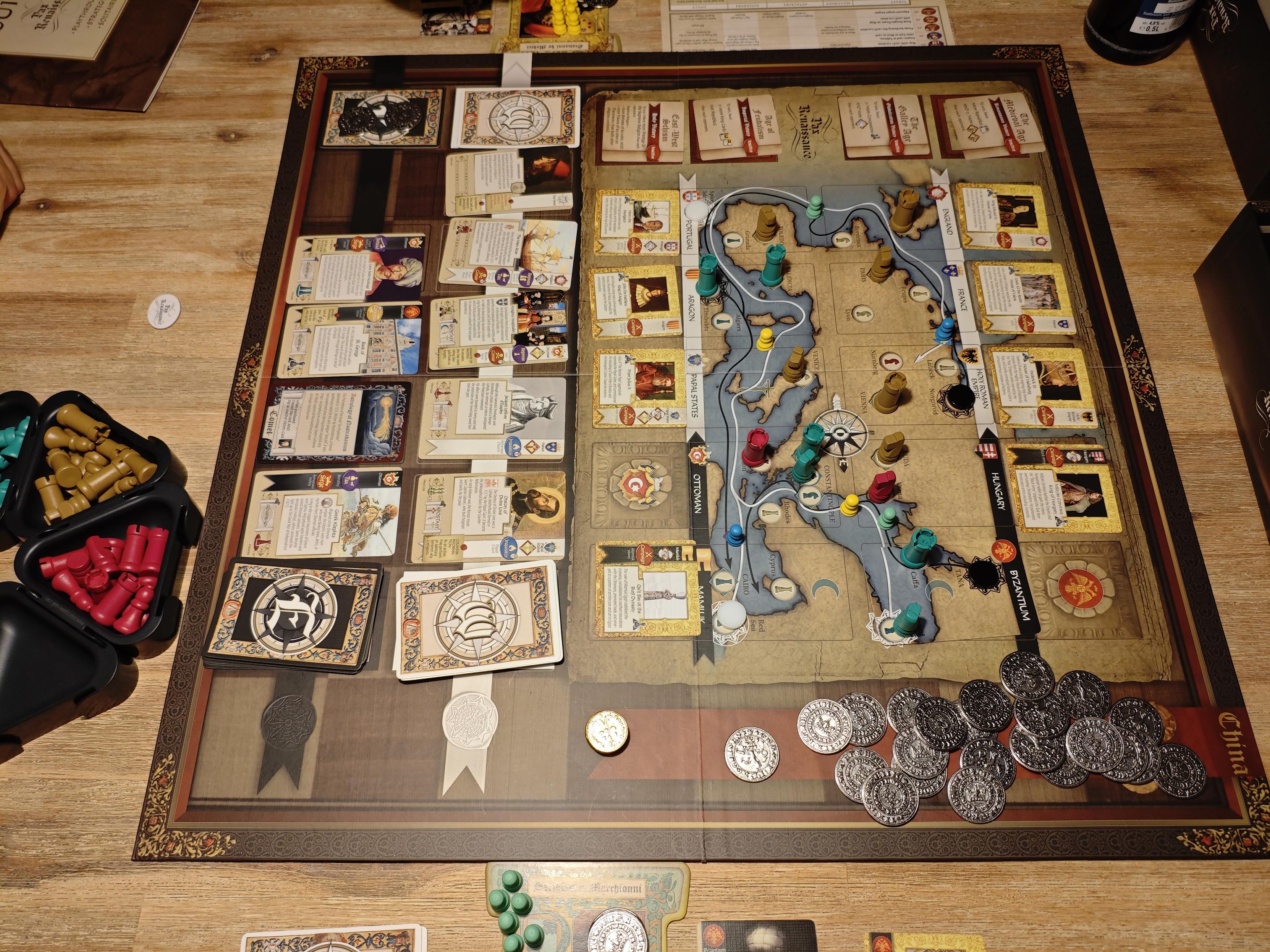 Holztisch mit dem spielbrett von pax Renaissance in der Mitte.